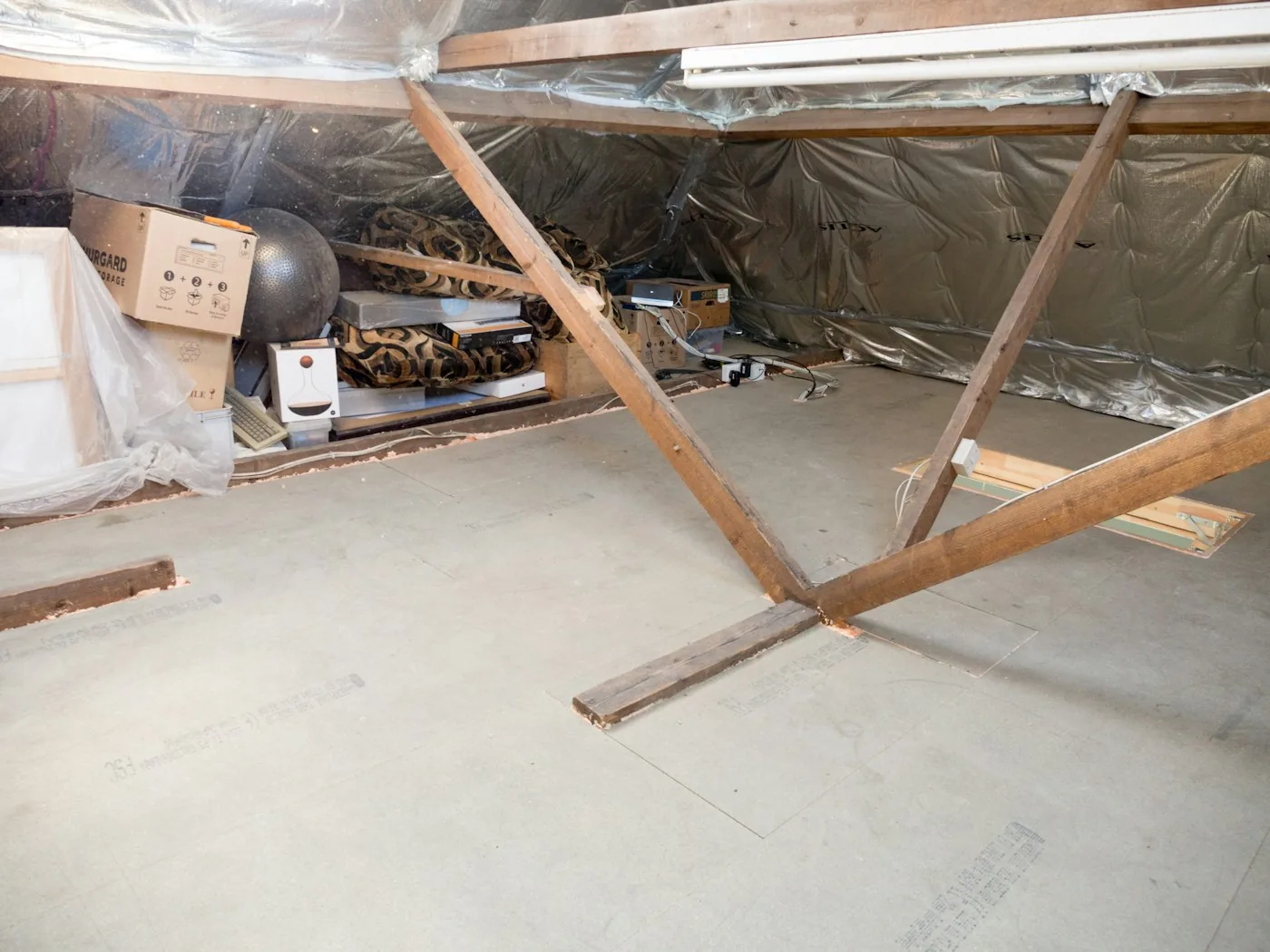 Technician with headlamp inspecting rafters and insulation in a Riverside attic for roof rat activity