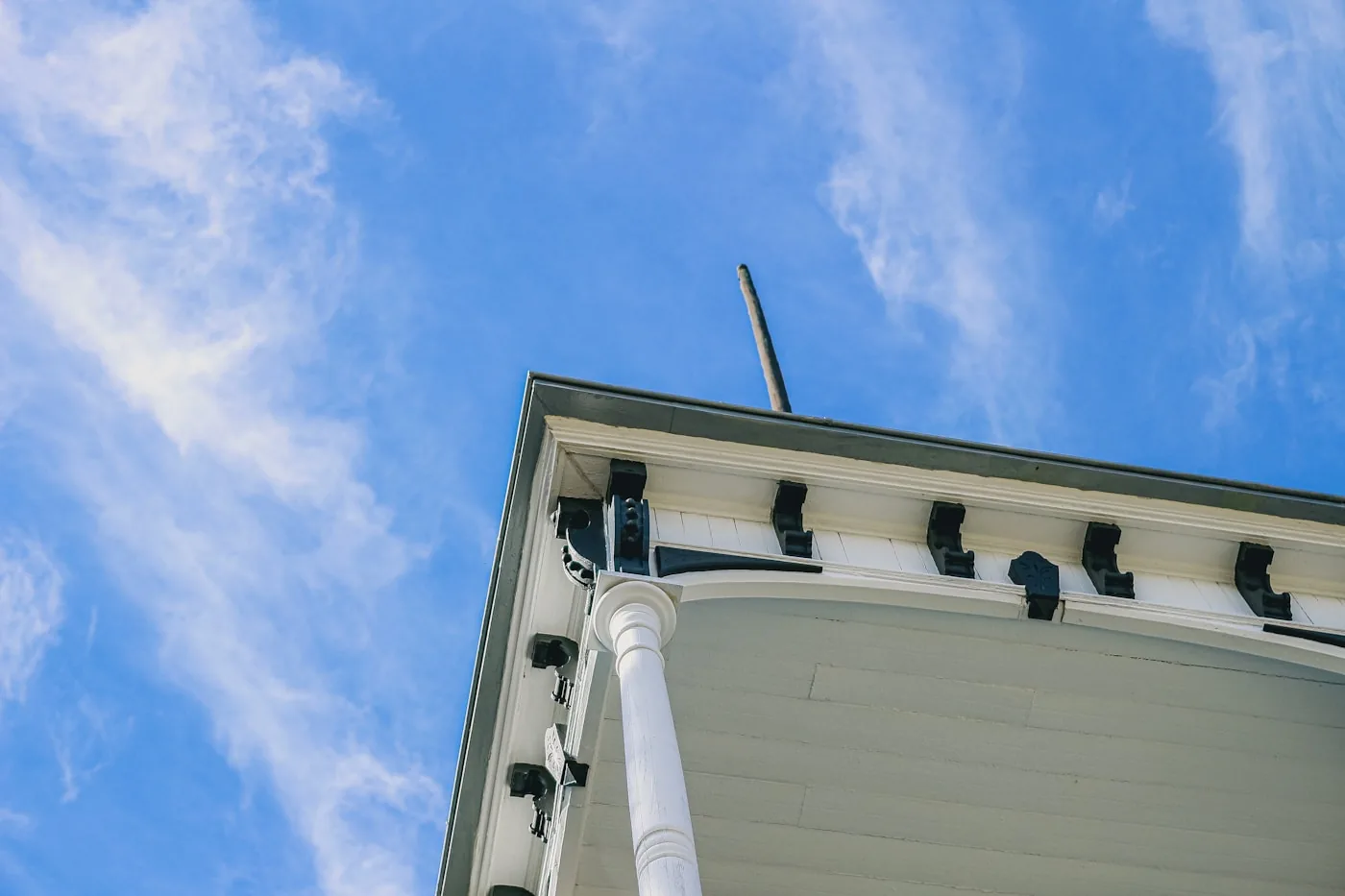 Gloved hands sealing a roofline vent on a stucco home with steel mesh and sealant